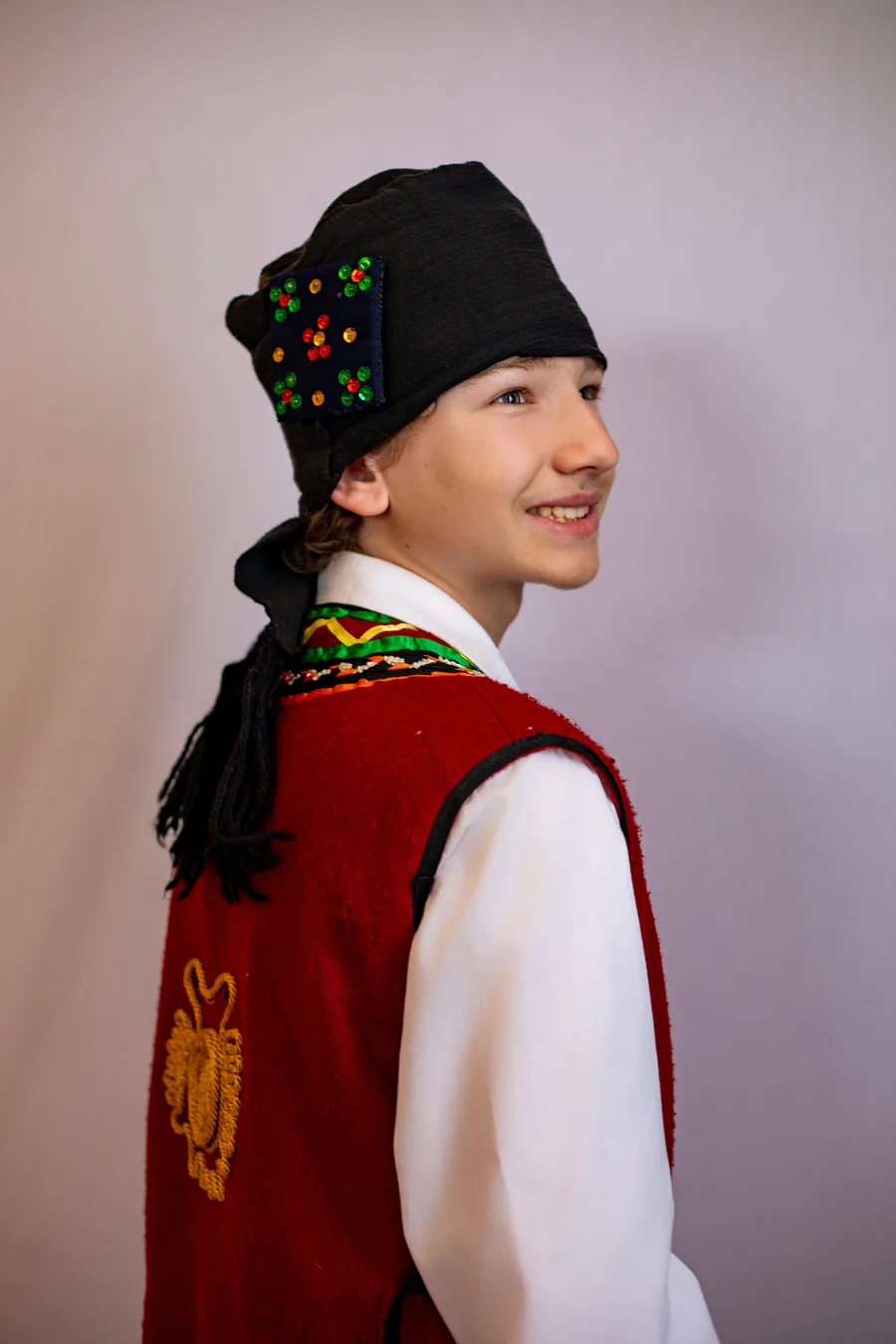 A young performer in traditional Greek regional folk costume with an embroidered vest and headscarf